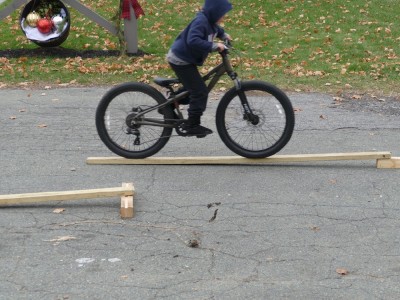 Zion riding his bike up a 2x4 ramp