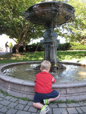 Lijah kneeling by a fountain to put his hands in