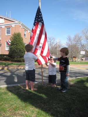 Harvey, Zion, and Nathan comparing their small flags to a big one