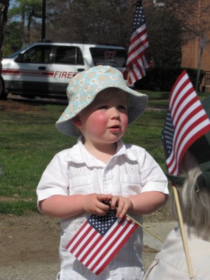 Zion, in a sun hat, holding a small American flag