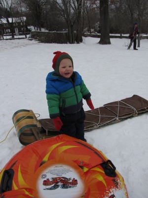 Lijah standing happily with the sleds