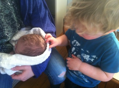 Lijah petting a month-old baby's head