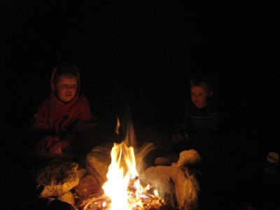 Harvey and Lijah sitting by the fire in the dark