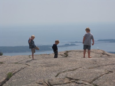 three boys barefoot atop a mountain