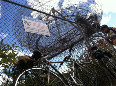 my bike leaning against the fence in front of the Millstone Hill Steerable Antenna; with Luke and warning sign