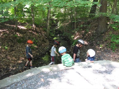kids wading in a stream with bike helmets on