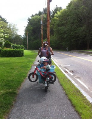 Leah riding the blue bike carrying Lijah and Zion; Zion's bike strapped on the back