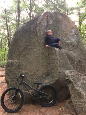 Zion halfway up a big rock, his bike leaning below him