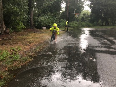 Zion riding his bike through a big puddle in the rain