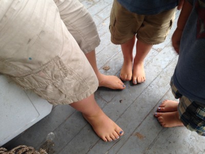 the three boys' feet, with blue-painted toenails