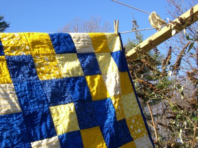 blue and yellow quilt hanging on the line