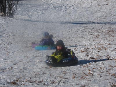 Zion and Nisia going down the hill in snowtubes