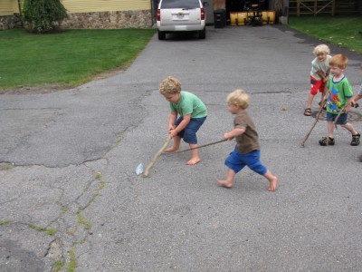 Harvey, Zion, and the other kids batting a bottle around the street with sticks