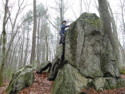 Elijah climbing up the side of a large boulder or outcropping
