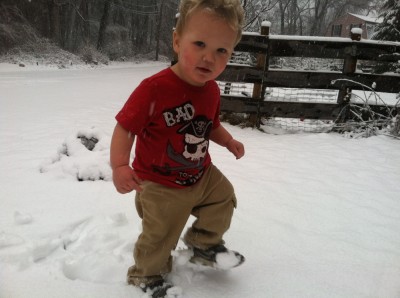 Lijah walking in the snow in a short sleeve shirt and Zion's sneakers