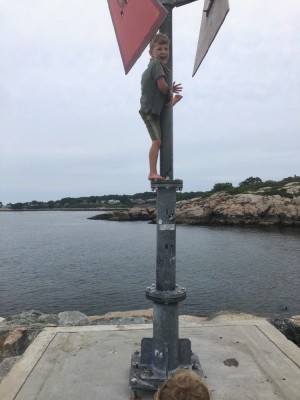 Elijah climbing a sign pole at the end of the breakwater