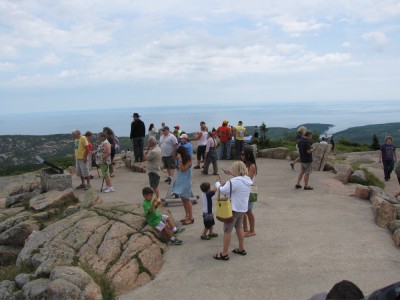 lots of people wandering around on a paved area atop Cadillac Mtn