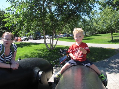 Lijah astride a giant cannon, Zion and Nathan lying down in the background