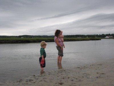 Harvey, and Leah holding Zion, wading in the gray water