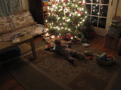 Lijah playing with presents in front of the Christmas tree