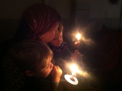 Mama, Zion, and Lijah cuddling by candlelight at church