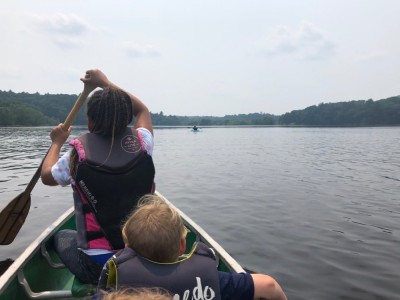 Nisia paddling the canoe with Zion as a passenger, Harvey in the kayak far ahead