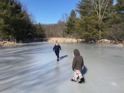 Zion running to slide on the cranberry bog ice, Lijah watching