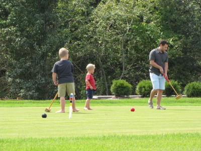 the boys and Uncle Jake playing croquet on a manicured lawn