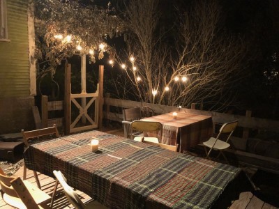 tables set with tablecloths and candles under the lights on our back deck