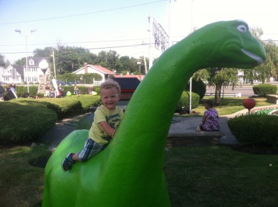 Lijah riding a green mini-golf brontosaurus