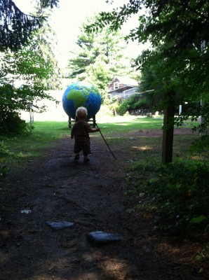 Lijah carrying a walking stick approaching a giant globe