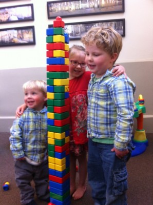 Zion, Taya, and Harvey posing by a tall tower of toddler Lego blocks