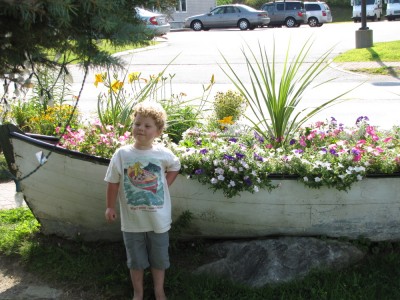 Harvey, in his Burt Dow shirt, posing by a dory planted with flowers