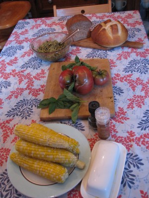 corn, tomatoes, basil, pesto spaghetti, and bread on the table