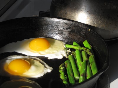 fried eggs and asparagus in the skillet