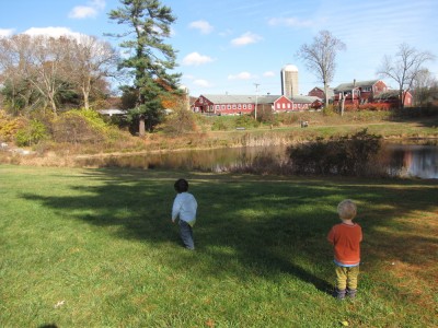Zion and a friend on a lawn with pond and farm behind them