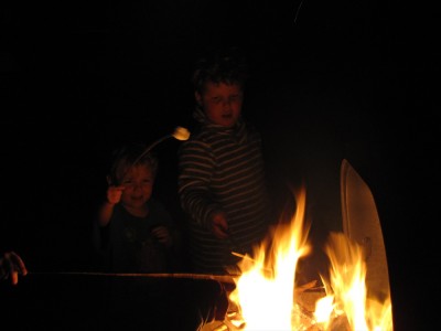 Harvey and Zion toasting marshmallows over a fire