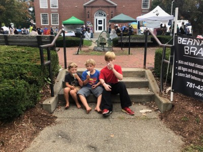 Zion, Elijah, and a friend sitting on little steps eating snowcones
