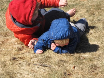 Harvey and Zion wrestling in the grass, bare-footed and winter-coated
