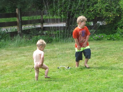 Harvey and Lijah playing in the sprinkler on the lawn