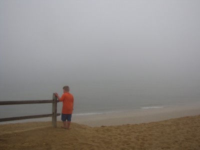 Harvey standing atop a dune bluff over the foggy atlantic