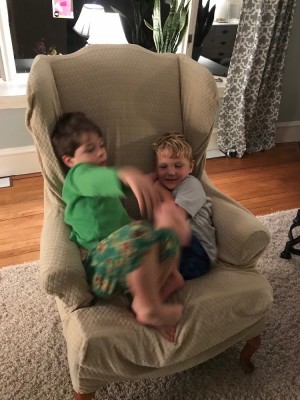 Lijah and Liam sleepily fooling around in an arm chair