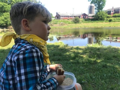 Lijah eating a sandwich by the pond at Great Brook