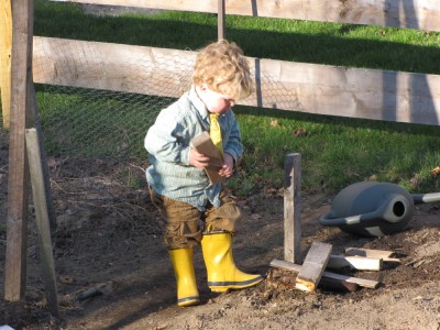 Harvey playing in the garden wearing yellow rain boots and a yellow tie
