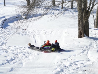 the bigger kids sledding down a hill in a bunch