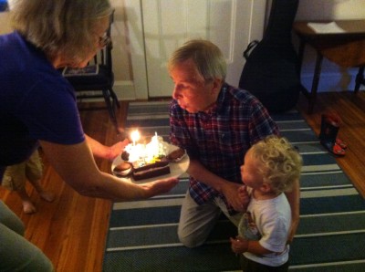 Grandpa David blowing out his birthday candles, Lijah by his side