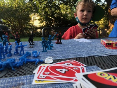 Lijah playing Uno on a table covered with plastic soldiers