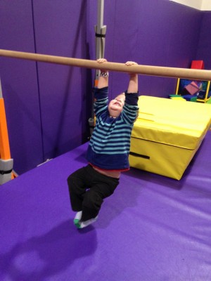 Lijah swinging from a bar at the playspace gym