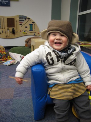 Lijah in the kids room at the library, in monkey hat