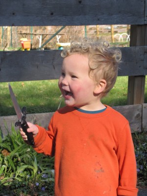 Lijah laughing by the fence, holding his little sword